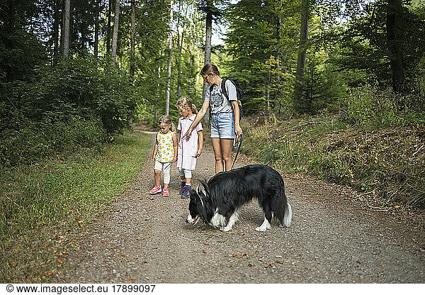 Woman with daughters and pet dog on footpath in forest