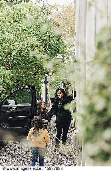 Woman with daughters at electric car charging station