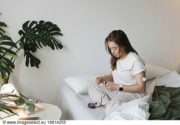 Woman with diabetes measuring blood glucose with glucometer at home