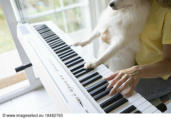 Woman with dog playing piano at home