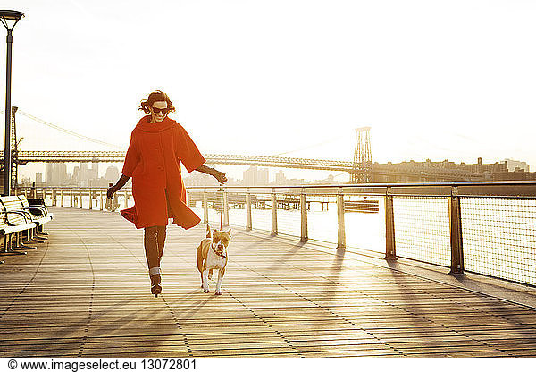 Woman with dog running on promenade against Williamsburg Bridge