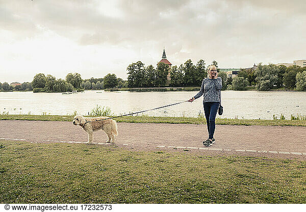 Woman with dog talking on smart phone at lakeshore