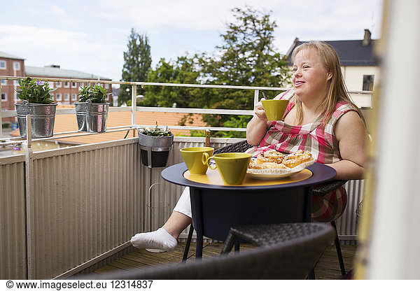 Woman with down syndrome enjoying meal on balcony
