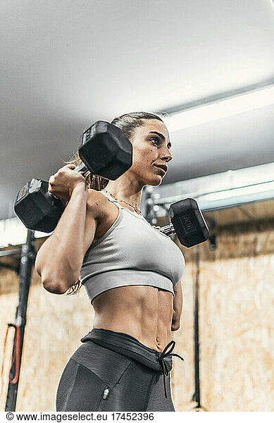 woman with dumbbells in the gym doing crossfit