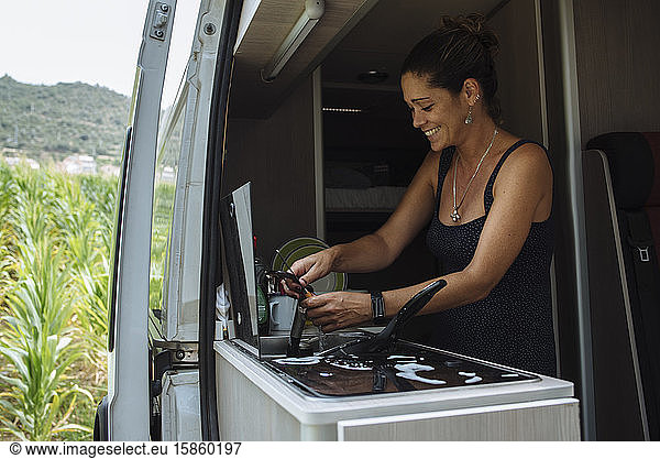 Woman with earrings washing dishes in motorhome during a vacation.