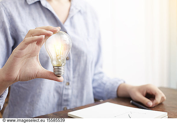 Woman with electric bulb planning how to save energy and money