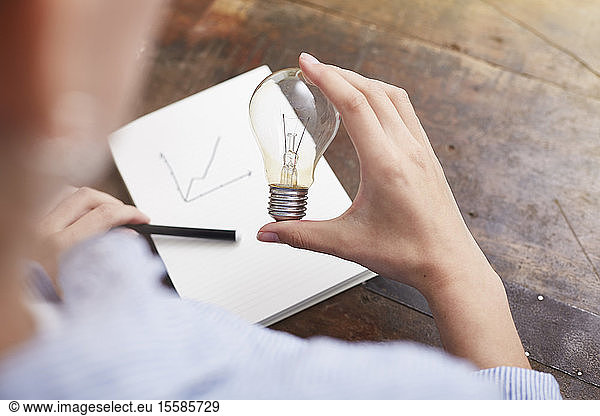 Woman with electric bulb planning way to save energy and money