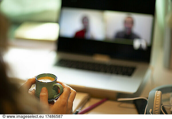 Woman with espresso video chatting with colleagues at laptop