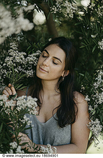 Woman with eyes closed amidst flowers