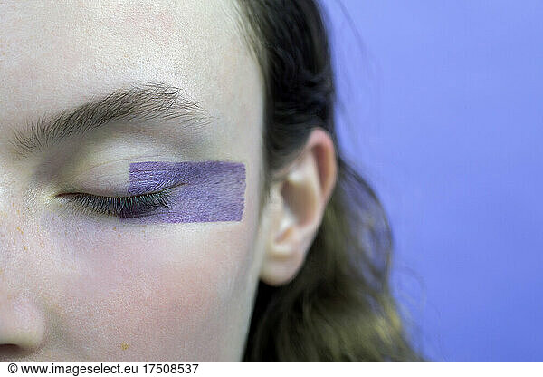 Woman with eyes closed and make-up against lavender background