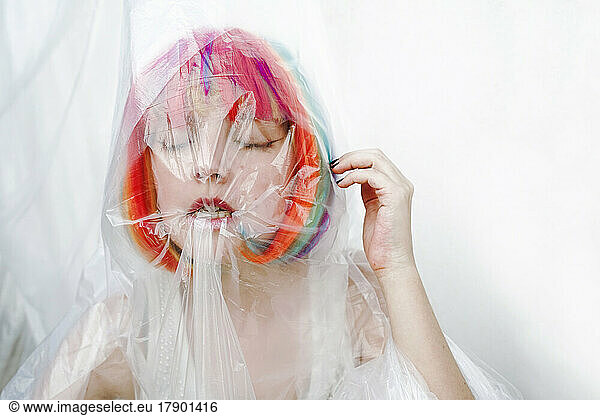 Woman with eyes closed biting plastic