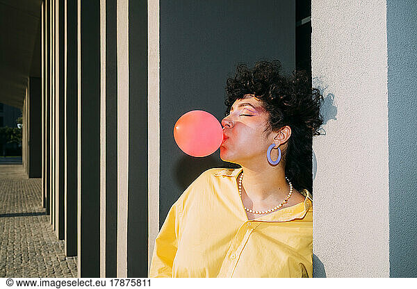 Woman with eyes closed blowing bubble gum on sunny day