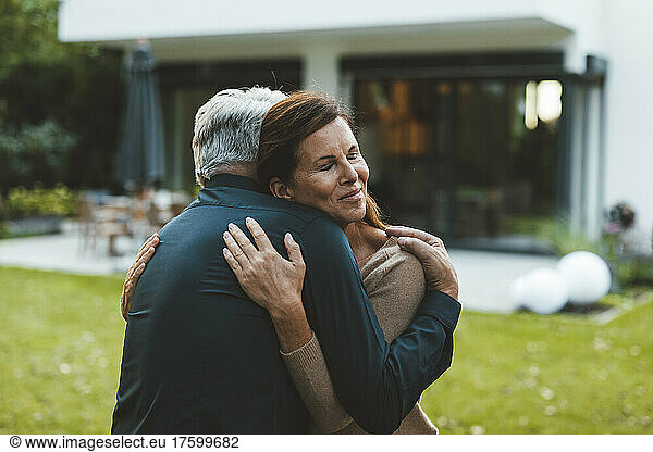 Woman with eyes closed hugging man at backyard