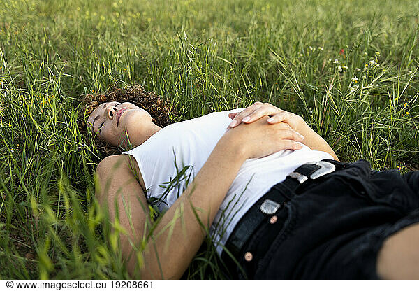 Woman with eyes closed lying on grass