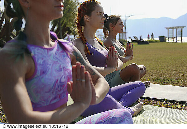 Woman with eyes closed meditating with friends at park