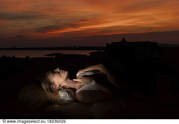 Woman with eyes closed relaxing at sunset