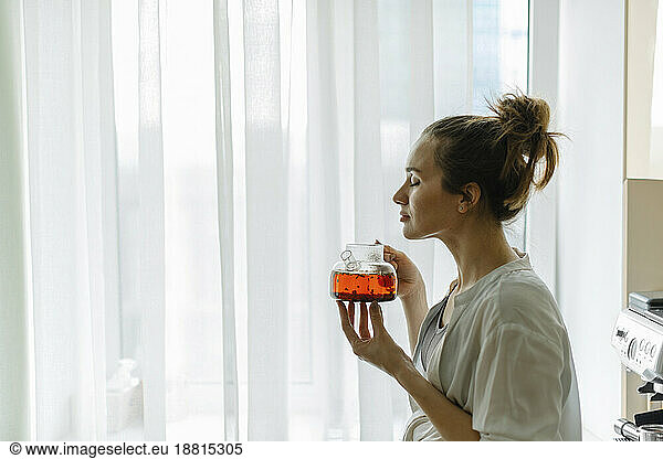 Woman with eyes closed smelling freshly brewed tea