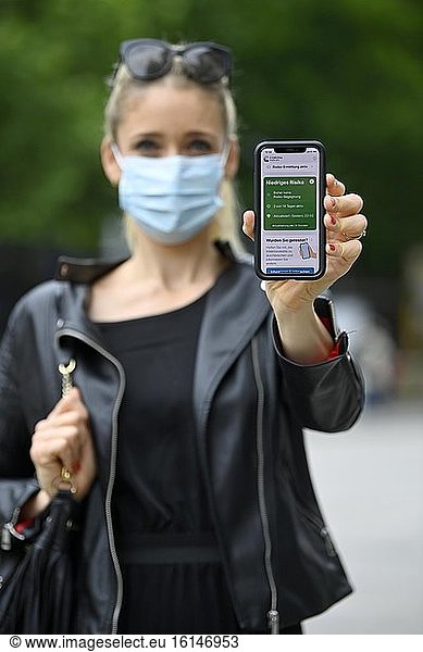 Woman with face mask shows smartphone with corona warning app  low risk  corona crisis  Baden-Württemberg  Germany  Europe