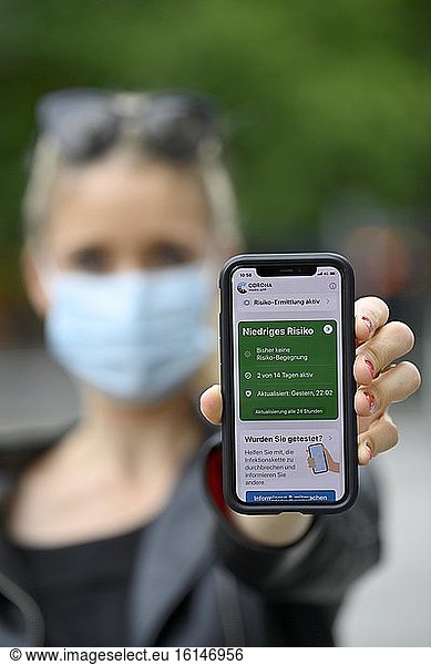 Woman with face mask shows smartphone with corona warning app  low risk  corona crisis  Baden-Württemberg  Germany  Europe