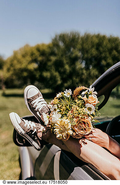 Woman with feet outside of truck window with a bouquet during summer