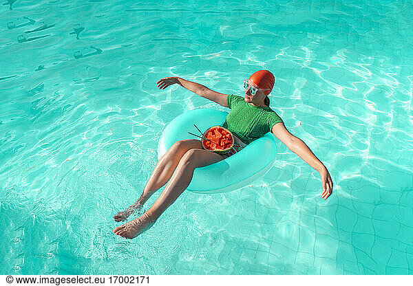 Woman with floating tire and watermelon in swimming pool