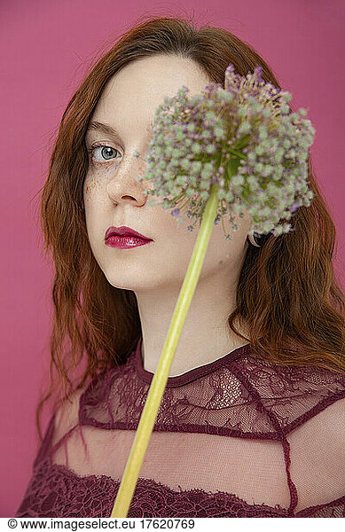 Woman with flower against pink background
