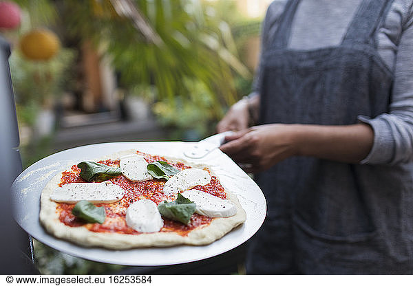 Woman with fresh homemade margherita pizza on peel