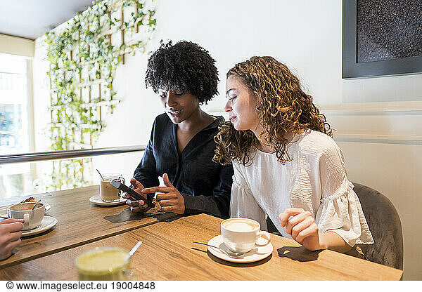 Woman with friend using smart phone in cafe