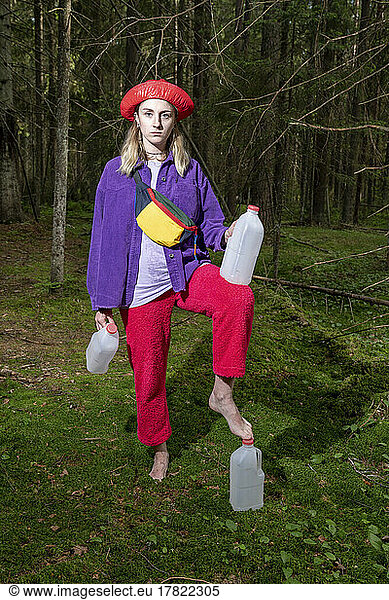Woman with gallon containers standing in forest