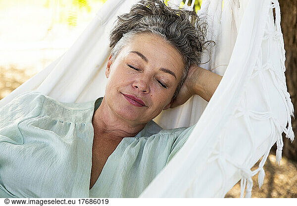 Woman with hand behind head sleeping in hammock