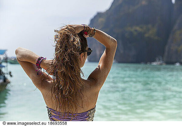 Woman with hand in hair looking at sea