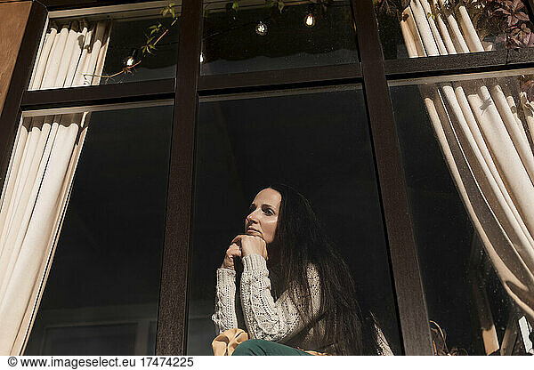 Woman with hand on chin looking out of window