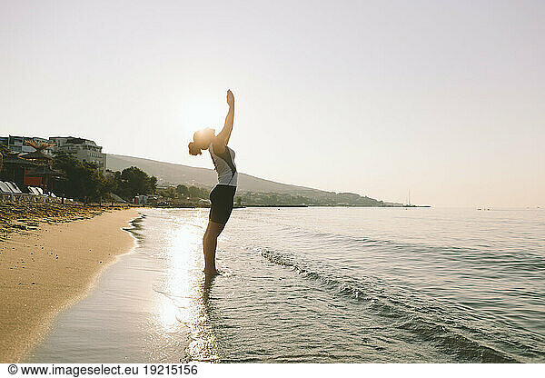Woman with hands clasped practicing yoga on sunny day at beach