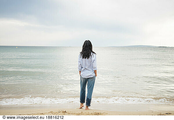 Woman with hands in pockets looking at sea