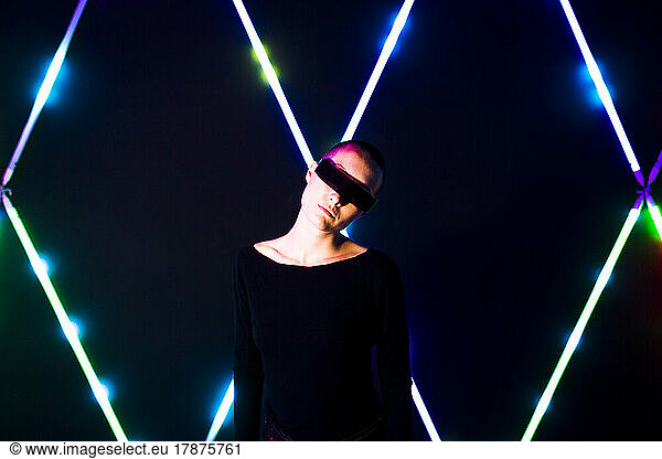 Woman with head cocked wearing smart glasses in front of illuminated lights