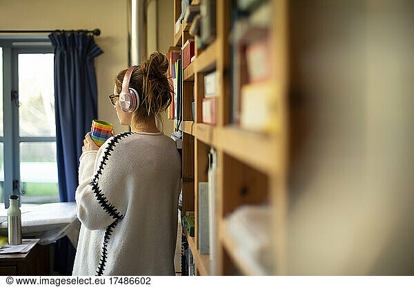 Woman with headphones and coffee in home office