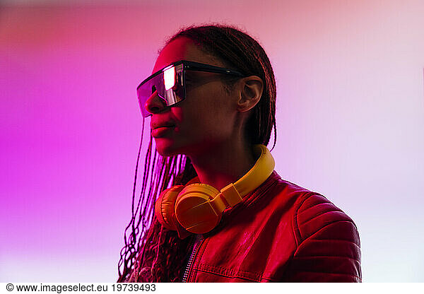 Woman with headphones wearing sunglasses in illuminated studio