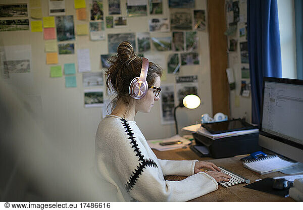 Woman with headphones working from home at computer in home office