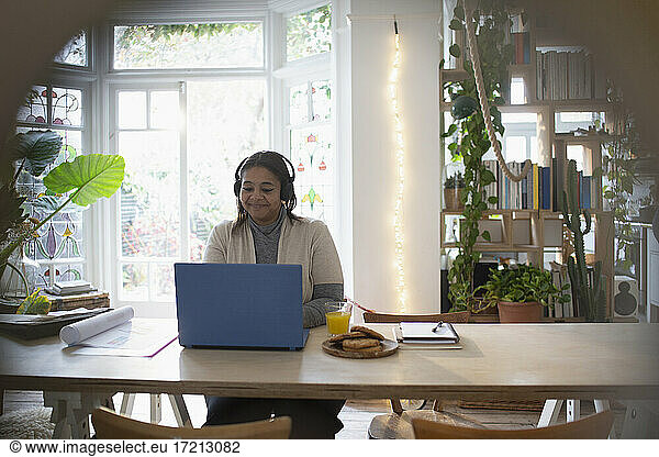 Woman with headphones working from home at laptop