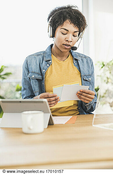 Woman with headset working at desk at home