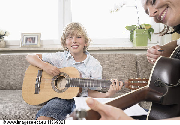 Woman with her son playing guitar in living room