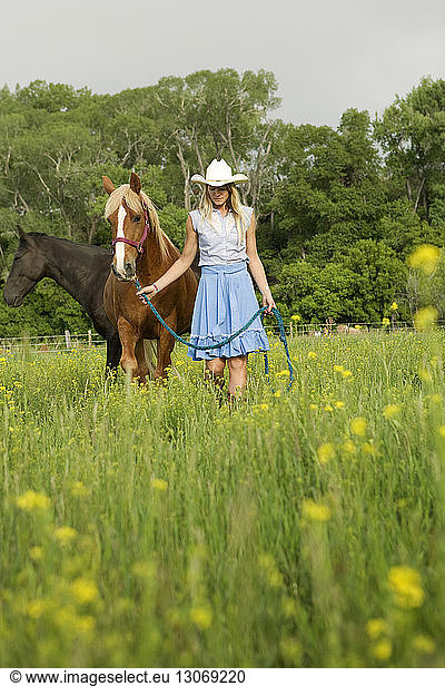 Woman with horses walking on grassy field