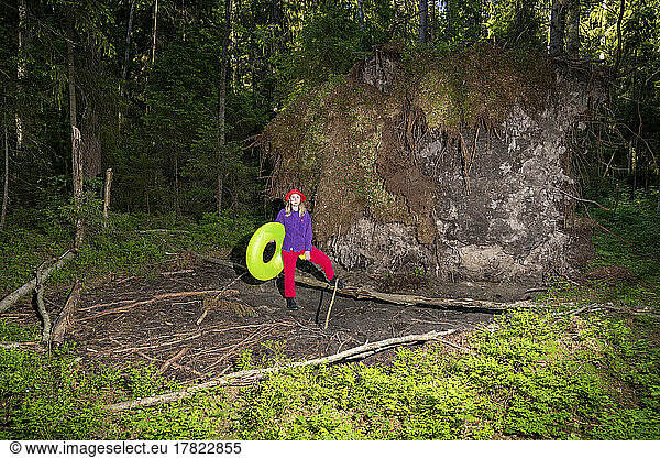 Woman with inflatable ring standing in forest