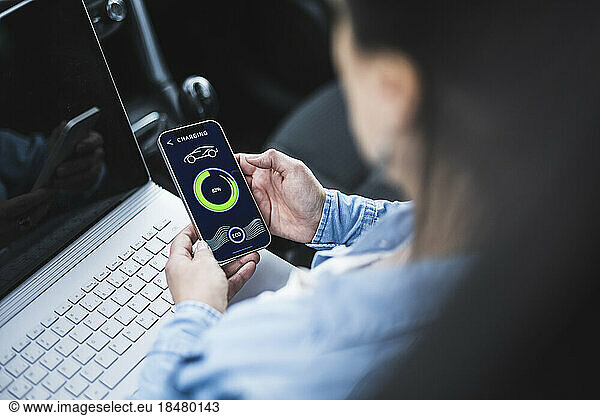 Woman with laptop examining electric car charging app