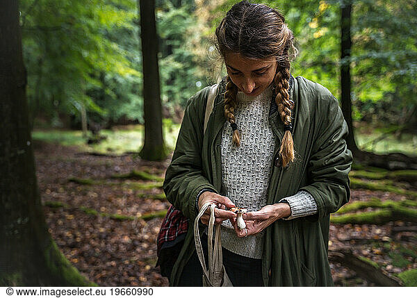 Woman With Long Braids Identifying Mushrooms In Scandinavia