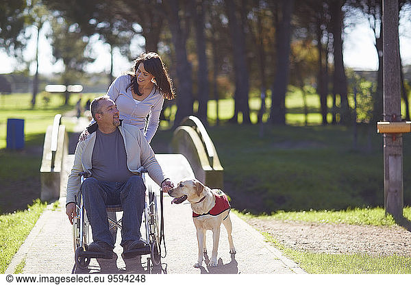Woman with man in wheelchair and dog in park