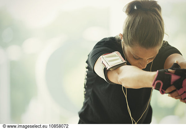 Woman with mp3 player armband stretching arms