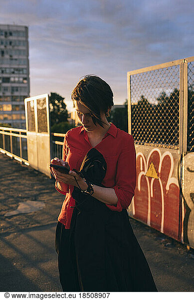 woman with phones in hand dials the number during sunset