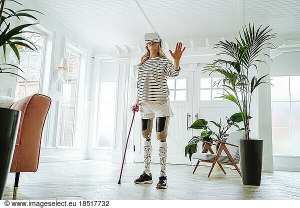 Woman with physical disabilities wearing virtual reality simulator gesturing at home
