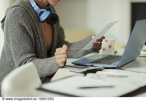 Woman with receipt paying bills at laptop